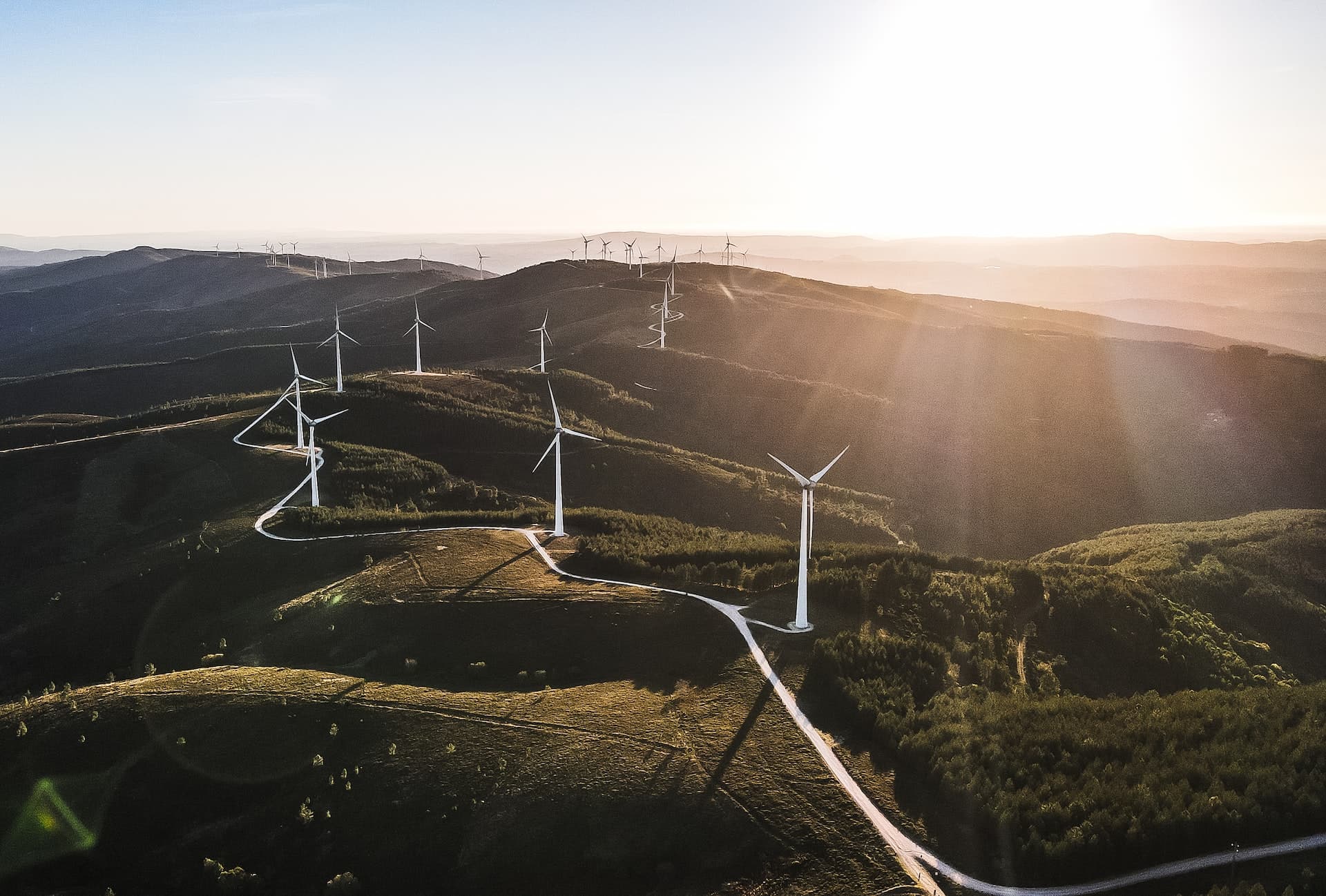 wind turbines on a hill with the sunset behind them